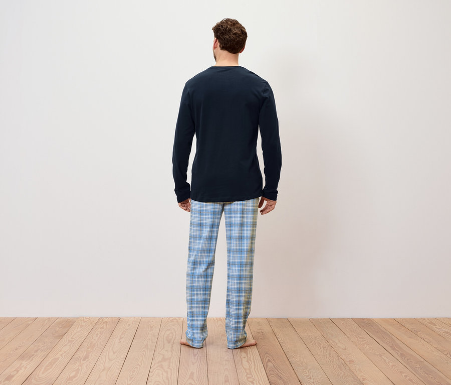 Mann von hinten trägt einen blauen langärmeligen Pyjama und eine blau karierte Hose.