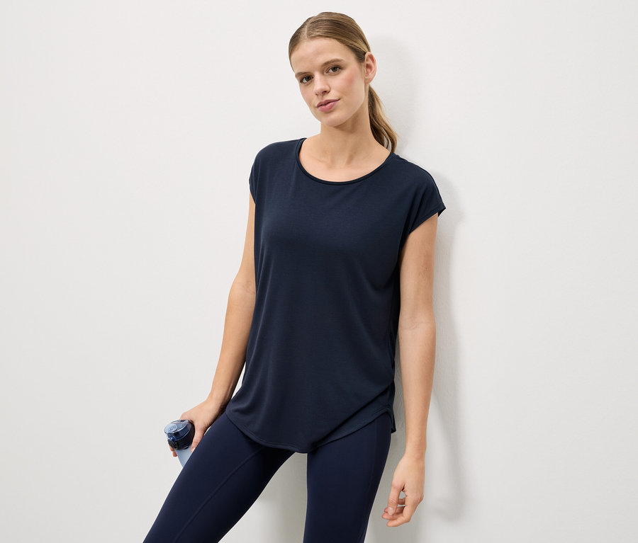 Frau mit blauem T-Shirt und Leggings, hält eine blaue Wasserflasche.