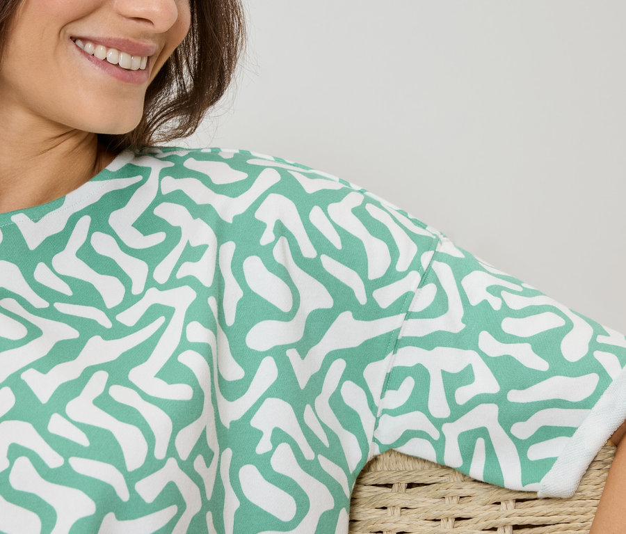 Frau trägt ein Oberteil mit grün-weißem Muster.