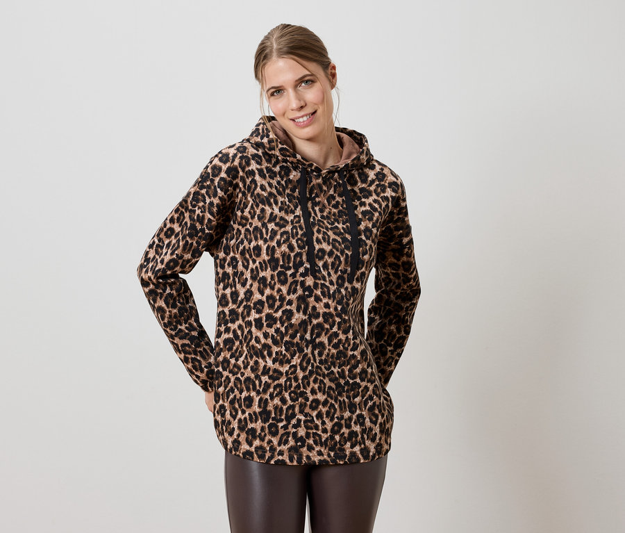 Frau trägt einen braunen Hoodie mit Leopardenmuster und braune Lederleggings.