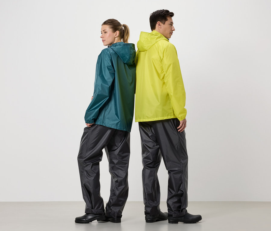 Eine Frau in einer blaugrünen Regenjacke und ein Mann in einer gelben Regenjacke stehen Rücken an Rücken vor einem weißen Hintergrund.