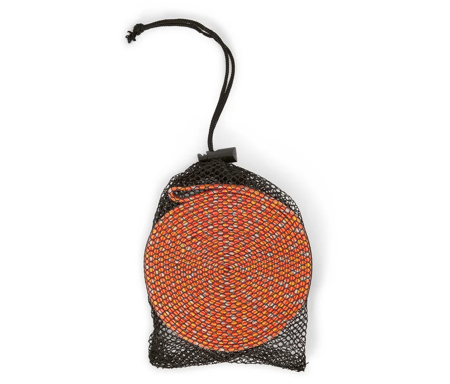 Eine orangefarbene, zusammengerollte Matte befindet sich in einem schwarzen Netzbeutel mit Kordelzug.