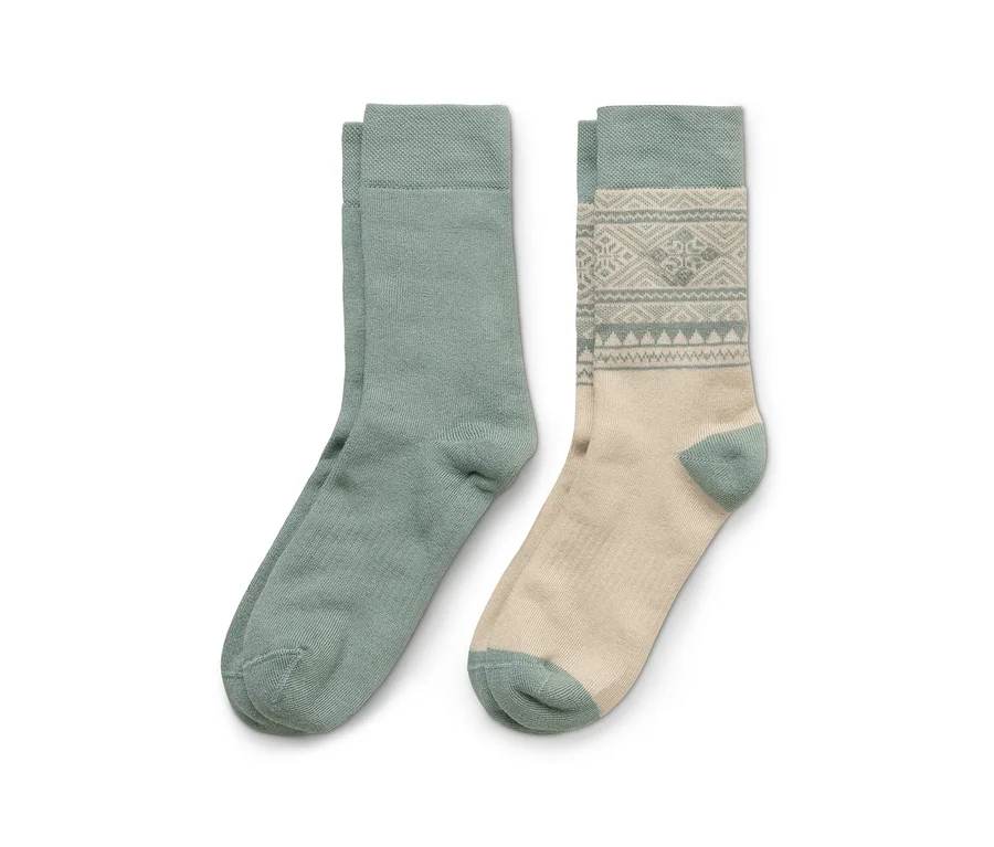 Zwei Socken liegen nebeneinander; eine ist einfarbig mintgrün, die andere beige mit mintgrünem Bündchen, Ferse und Spitze sowie einem mintgrünen geometrischen Muster.