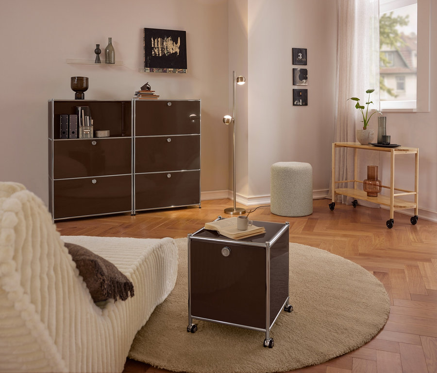 Modernes Wohnzimmer mit beigem Sofa, großer brauner Metall-Kommode »CN3« mit 3 Klappenfächern, kleinem braunen Metall-Rollcontainer »CN3« mit 2 Klappenfächern auf rundem Teppich, Bouclé-Sitzhocker und Servierwagen aus Holz.