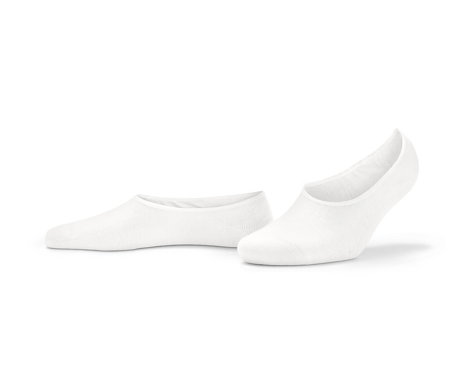 Zwei Paar weiße Sneaker-Füßlinge liegen auf dem Boden.