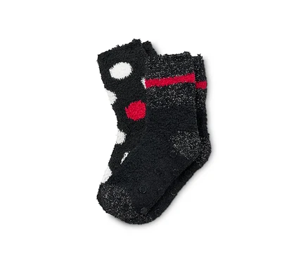 Zwei Paar flauschige, schwarze Kuschelsocken. Ein Paar ist mit weißen und roten Punkten, das andere mit roten Streifen.