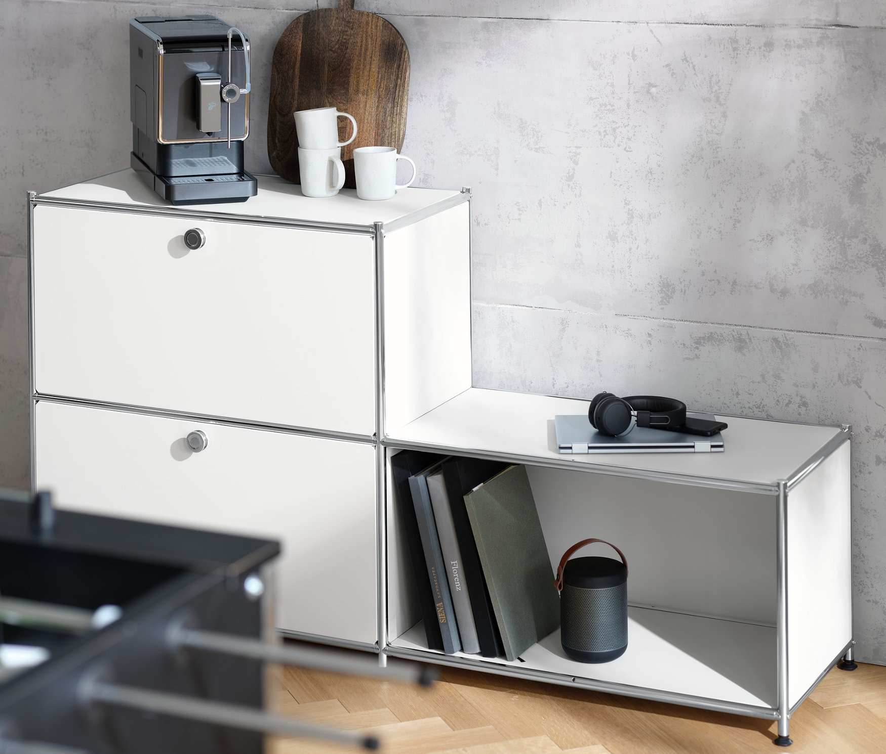 Kaffeemaschine steht auf einem weißen Metallregal »CN3« mit 3 Fächern. Auf dem Regal liegen auch Tasse, Brett und Kopfhörer.