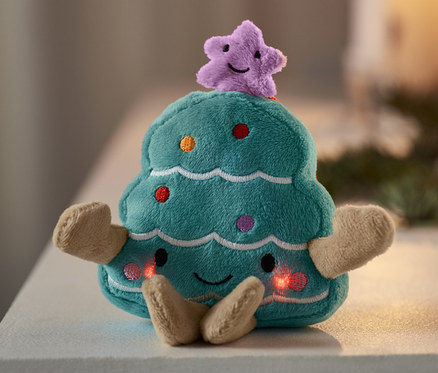 Singendes Mini-Plüschtier, Weihnachtsbaum steht auf einer weißen Oberfläche.