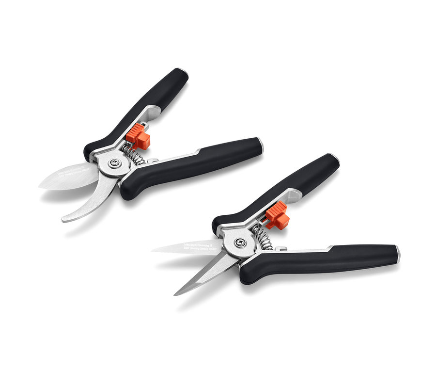 Zwei Mini-Pflegescheren liegen auf einer weißen Fläche.