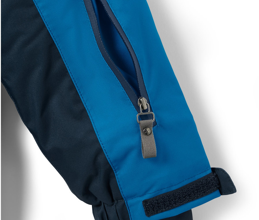 Detailansicht einer blau-dunkelblauen Kinder-Skijacke mit Reissverschlusstasche am Ärmel.