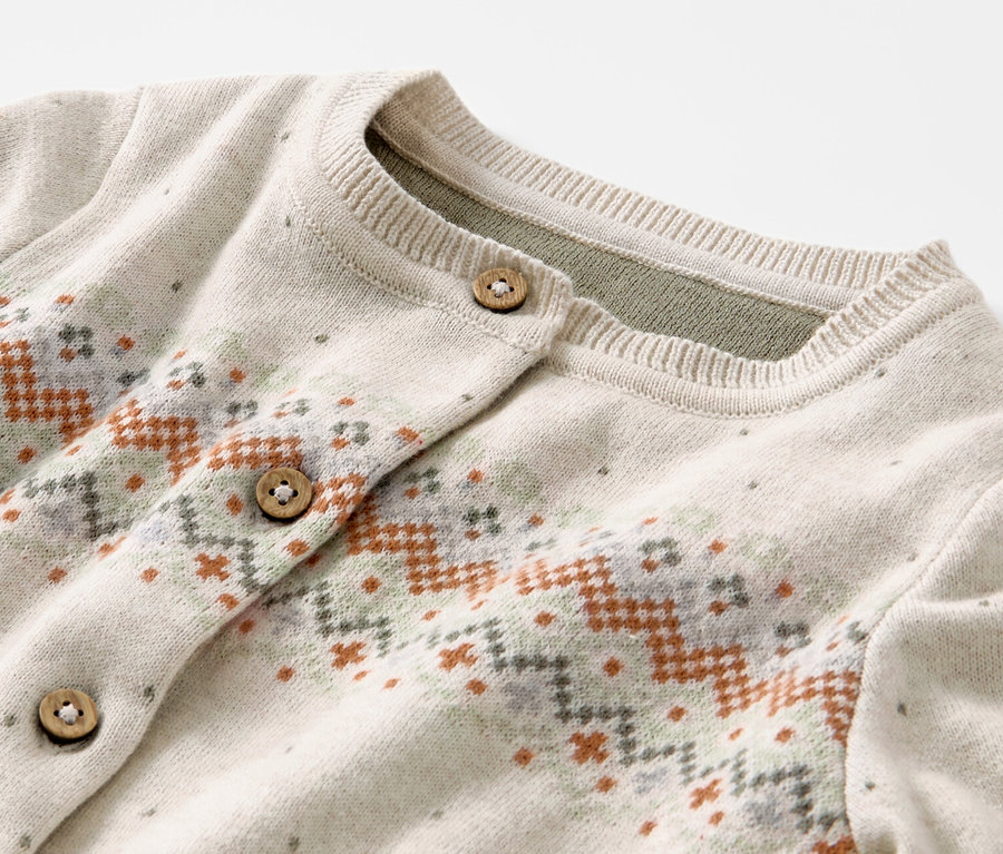 Detailansicht einer Kinder-Strickjacke mit Norwegermuster und Holzknöpfen.