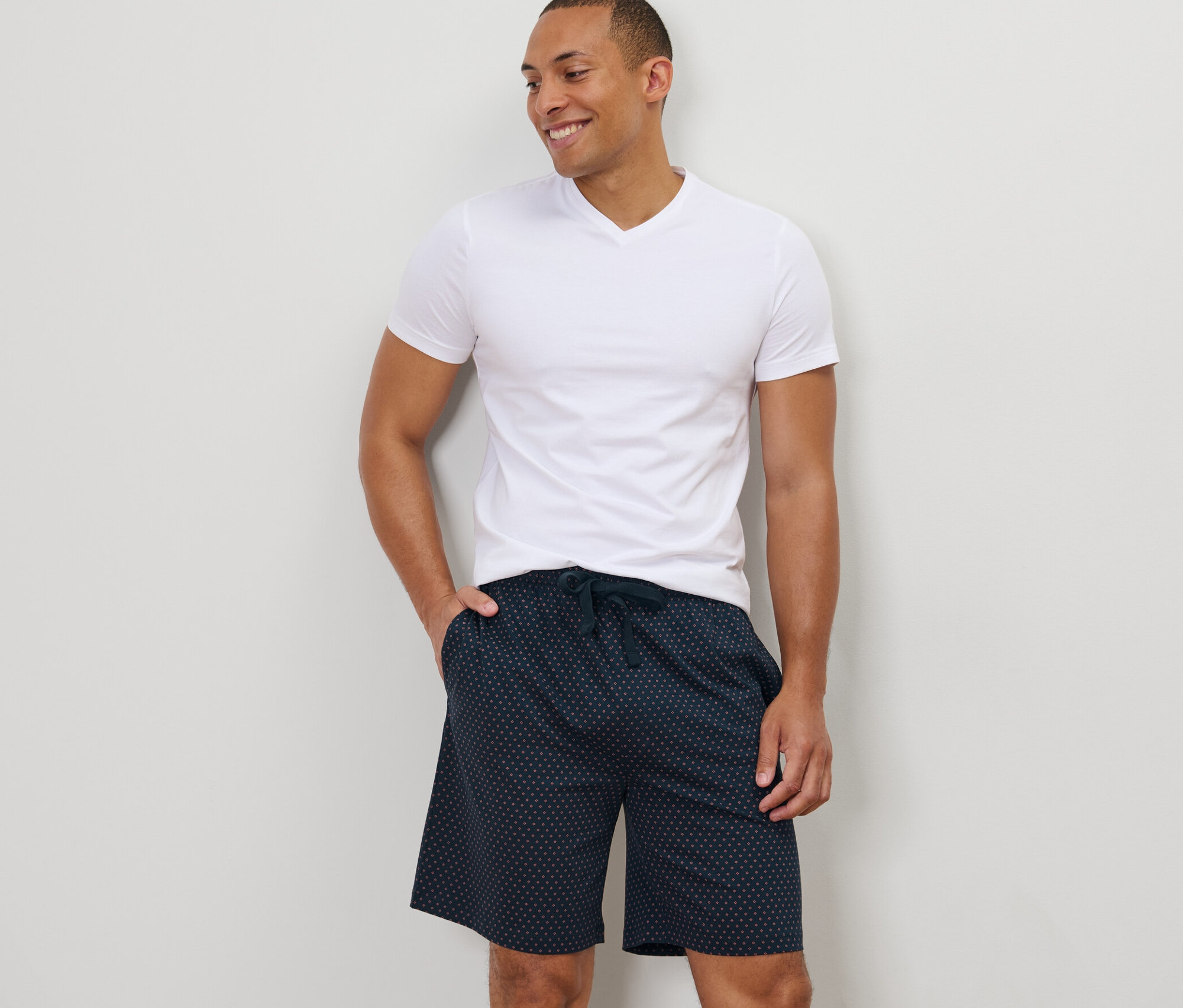 Mann steht mit der Hand in der Tasche der Relaxshorts.