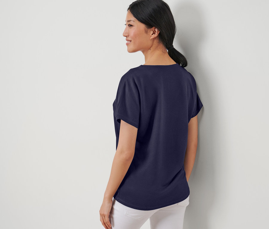 Frau posiert in einem dunkelblauen, strukturierten Shirt.