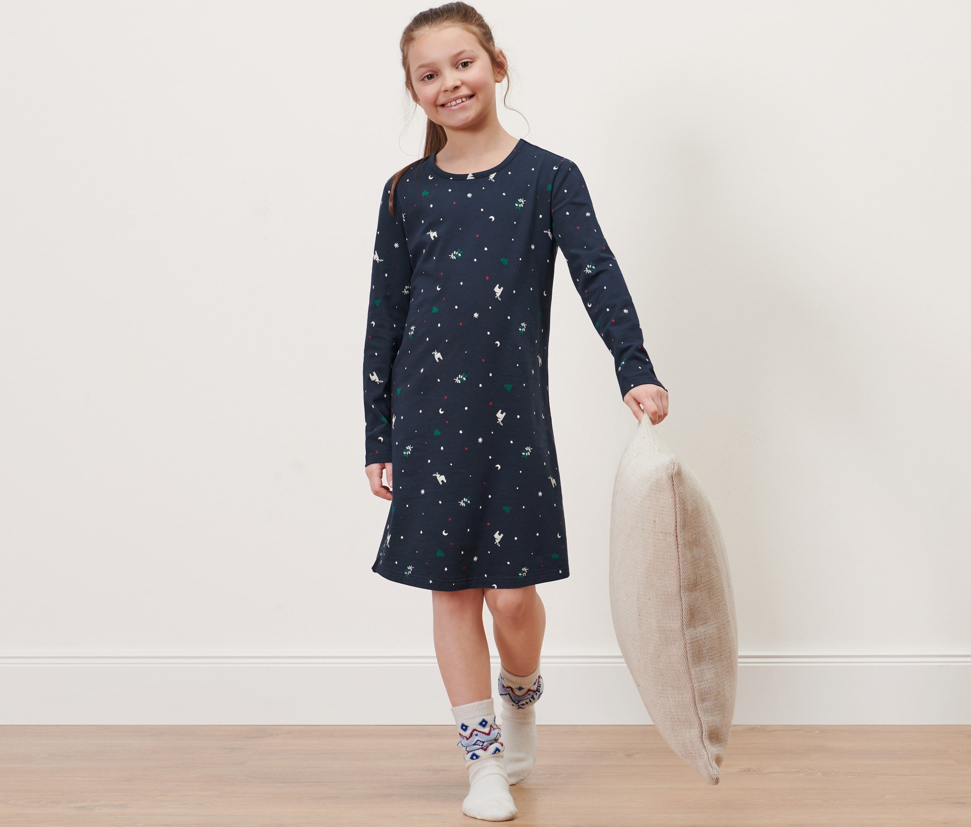 Mädchen im Kinder-Nachthemd hält ein Kissen.