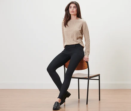 Eine Frau sitzt auf einem Stuhl und trägt schwarze Jeggings.