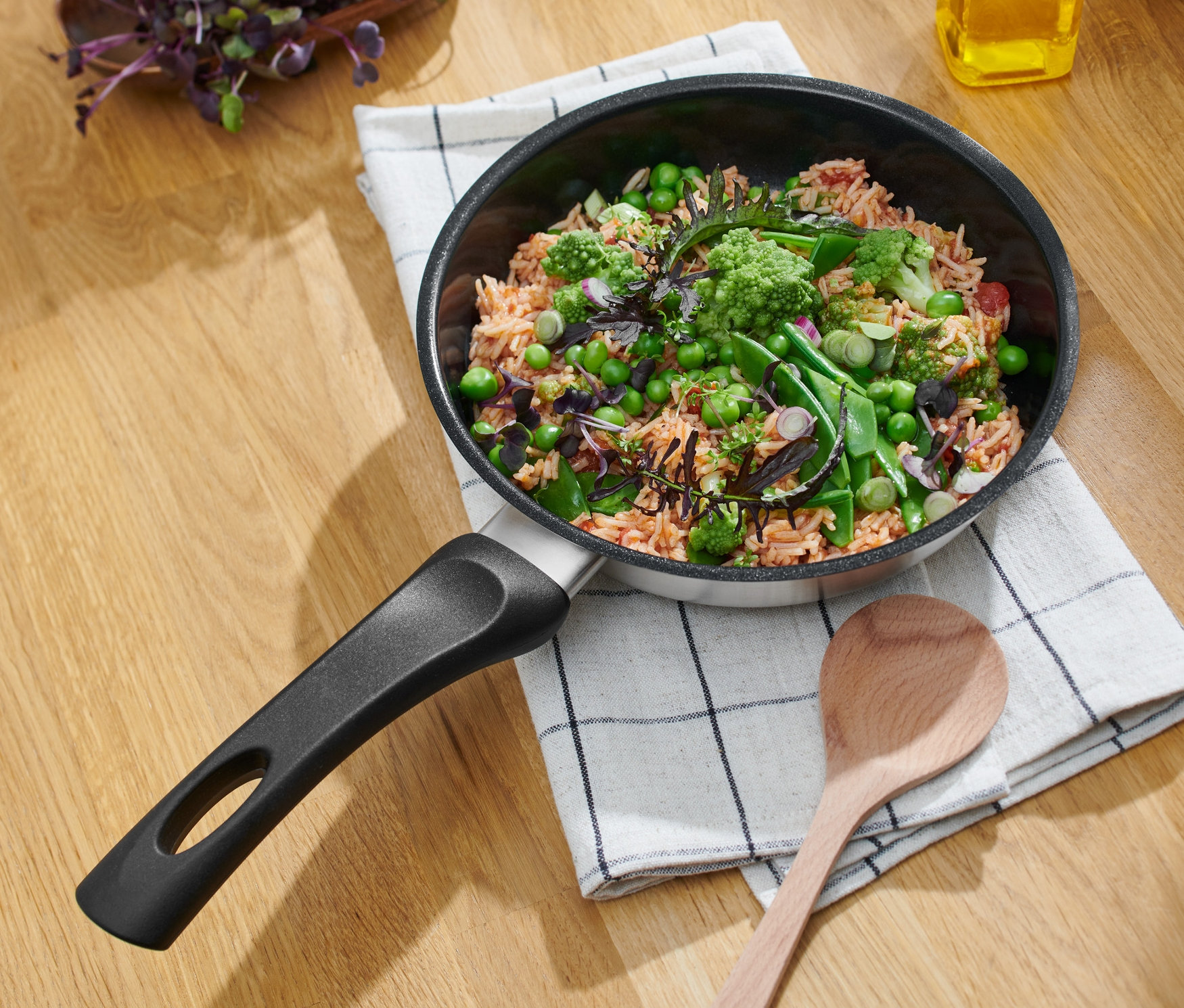 Edelstahl-Pfanne mit Keramikbeschichtung, Ø ca. 20 cm, mit Speisen auf einem Küchentuch mit Karomuster.