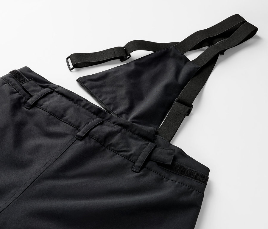 Detailaufnahme einer schwarzen Hose mit Latz und elastischen Trägern.
