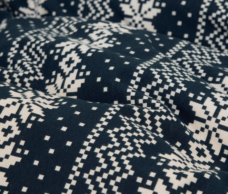Nahaufnahme eines Stoffes mit einem pixeligen Schneeflockenmuster in Dunkelblau und Weiß.