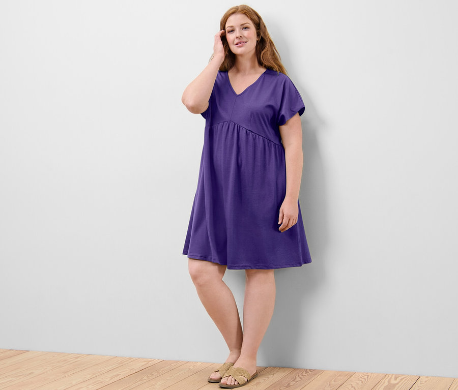 Frau posiert in einem lilafarbenen Jerseykleid.