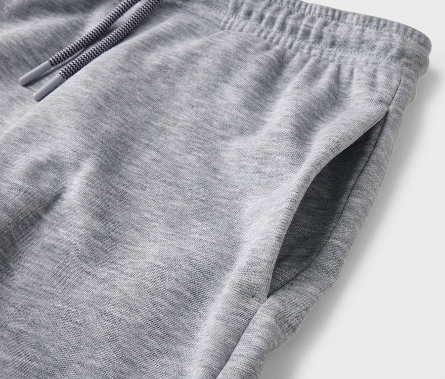 Detailaufnahme einer grauen Jogginghose mit Kordelzug und Hosentasche.