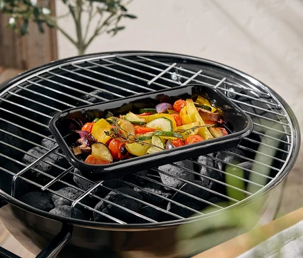 Gemüse in einer schwarzen Auflaufform auf einem Grill.