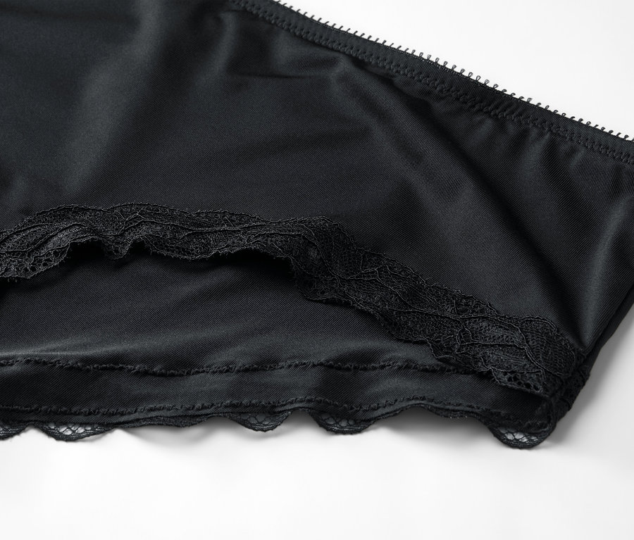 Nahaufnahme einer schwarzen Unterhose mit Spitzenbesatz auf weißem Hintergrund.