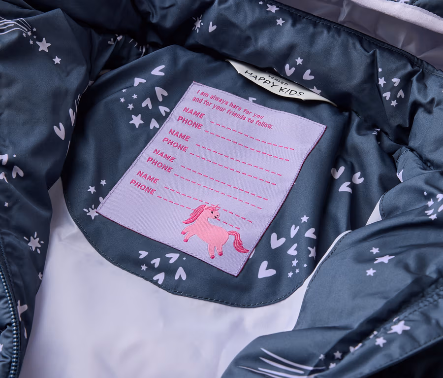 Innenansicht einer dunkelgrauen Tchibo HAPPY KIDS Jacke mit Sternen und Herzen, mit einem Etikett für Namen und Telefonnummern mit Einhorn.