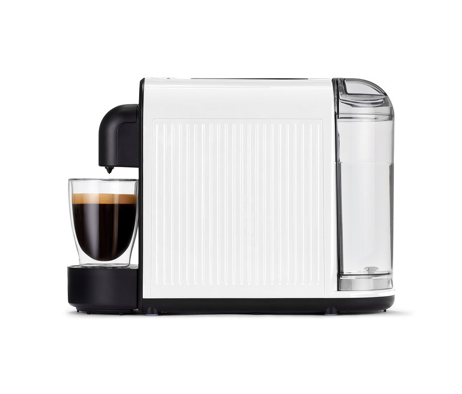 Die weiße Cafissimo now white Kaffeemaschine mit vollem Glas steht auf einem Tisch.