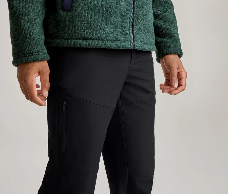 Person trägt eine grüne, texturierte Fleecejacke mit Reißverschluss und schwarze Hose mit Reißverschlusstasche am linken Oberschenkel.