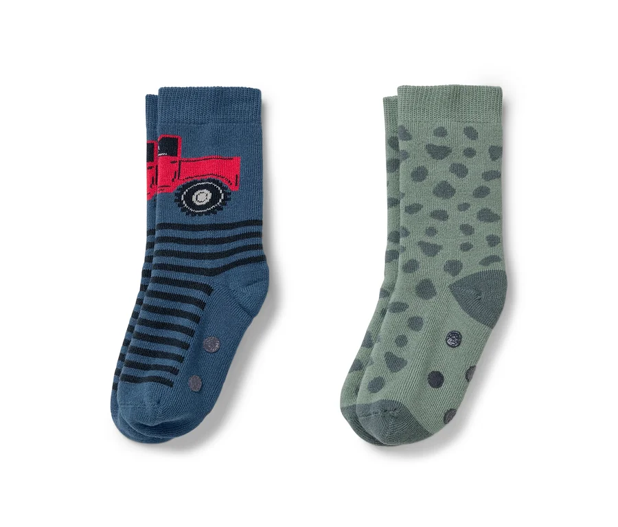 Zwei Paar Socken. Einmal blau mit rotem Lastwagen und Streifen, einmal grün mit dunkelgrünen Punkten.