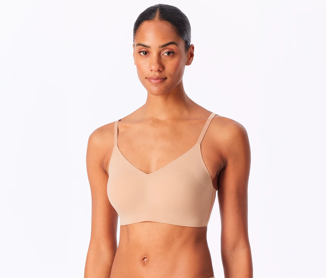 Eine Frau mit dunkler Haut und zurückgebundenem Haar trägt ein ahornfarbenes SCHIESSER Invisible Bustier mit Pads und blickt direkt in die Kamera.
