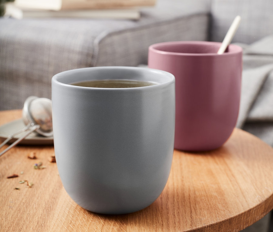 Zwei Trinkbecher stehen auf einem Holztisch.