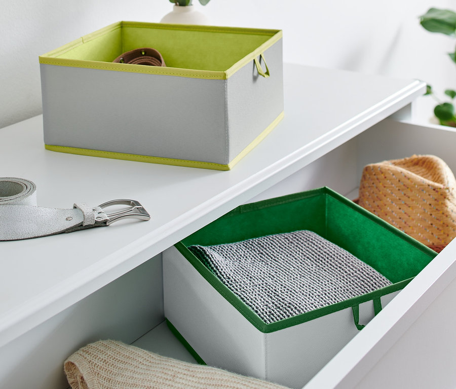 Auf einer weißen Kommode liegen zwei große Schubladen-Ordnungsboxen und ein silberner Gürtel.