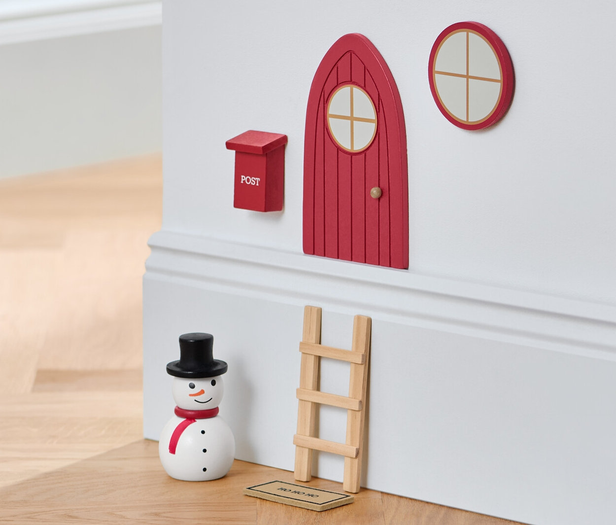 Ein Wichteltür-Set an einer Wand mit einem Schneemann und einem Hocker.