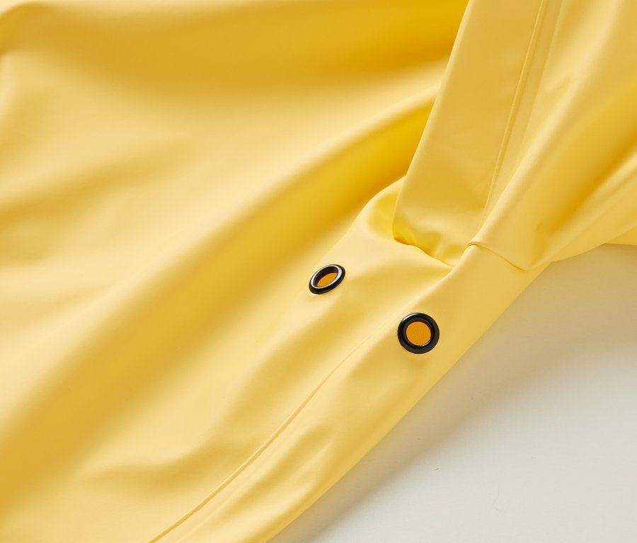 Detailansicht eines gelben Regenparkas »Friesennerz« mit schwarzen Ösen.