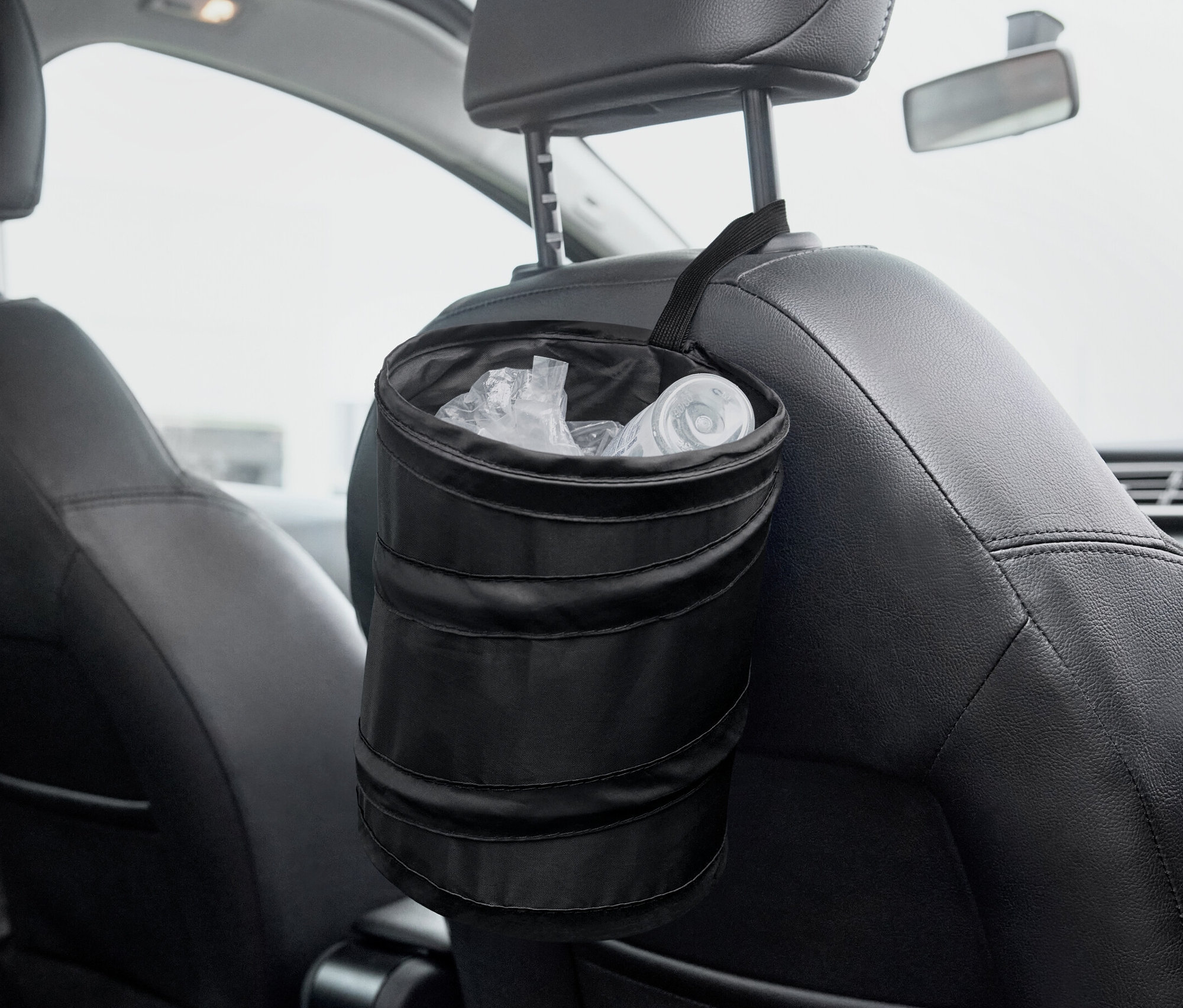 Ein schwarzer, faltbarer Mülleimer hängt an der Rückseite eines Autositzes.