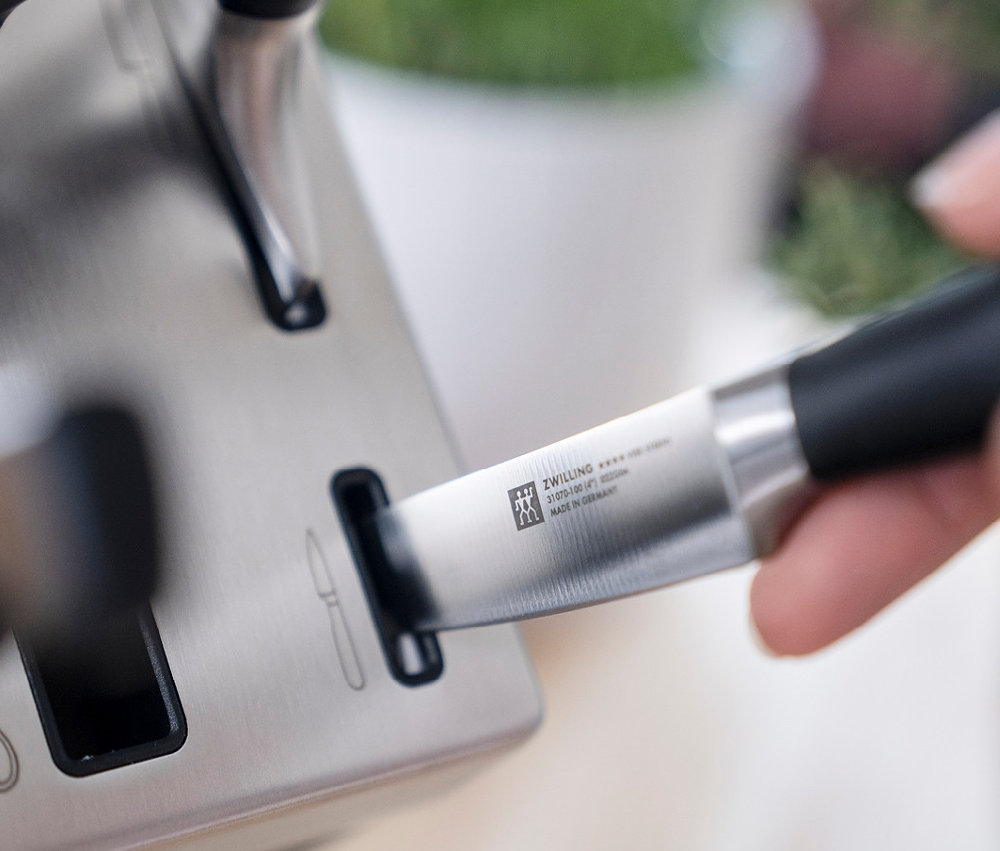 Messer wird in den ZWILLING **** VIER STERNE Selbstschärfenden Messerblock gesteckt.