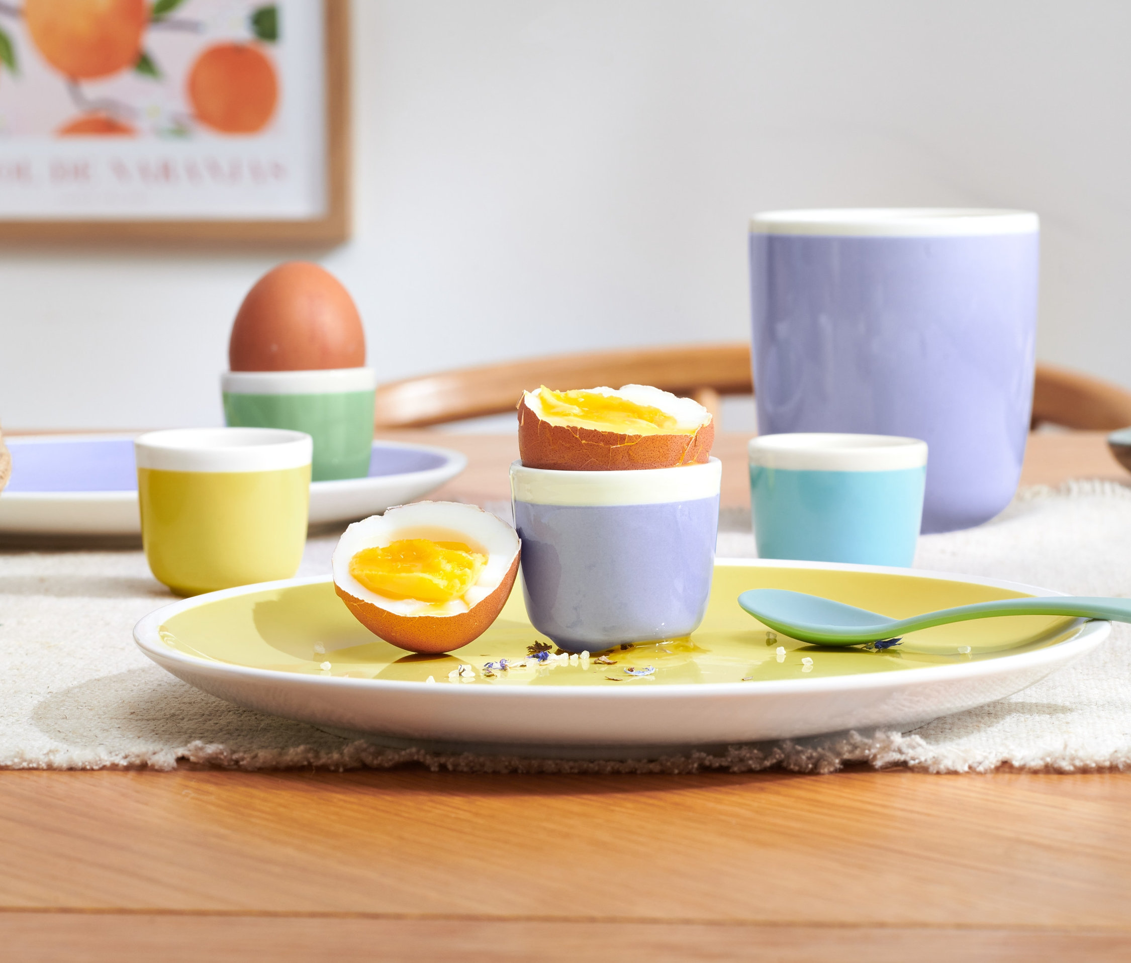 Halbiertes Ei im Eierbecher auf gelbem Teller und 3 weitere Eierbecher.
