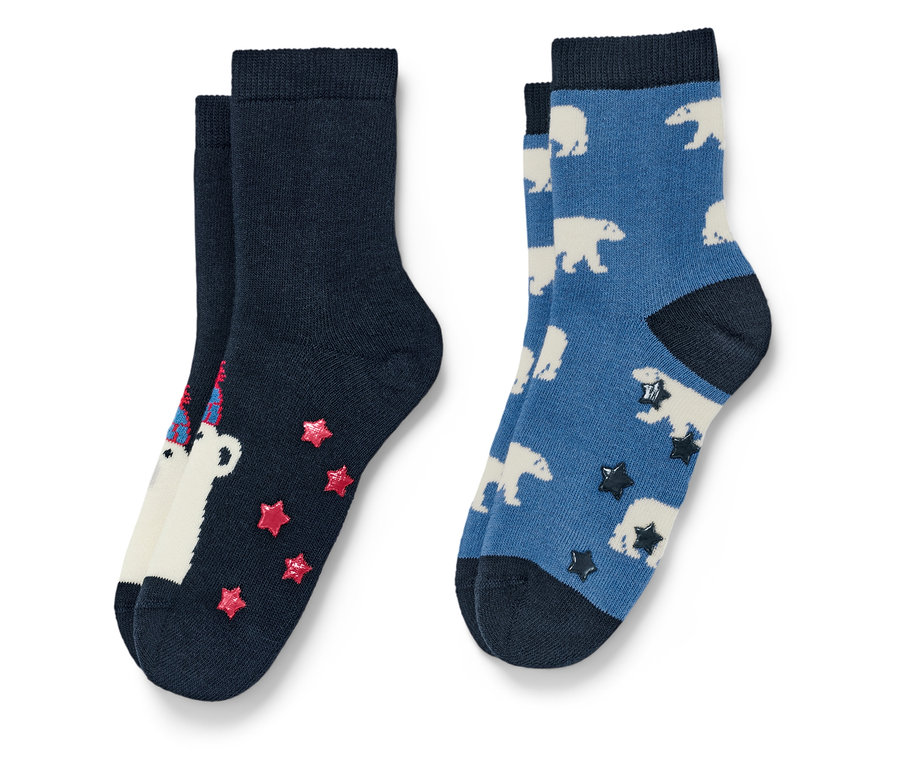 Zwei Paar Socken. Ein Paar ist marineblau mit einem weißen Bären mit Geburtstagshut und roten Sternen, das andere Paar ist blau mit weißen Eisbären und dunklen Sternen.