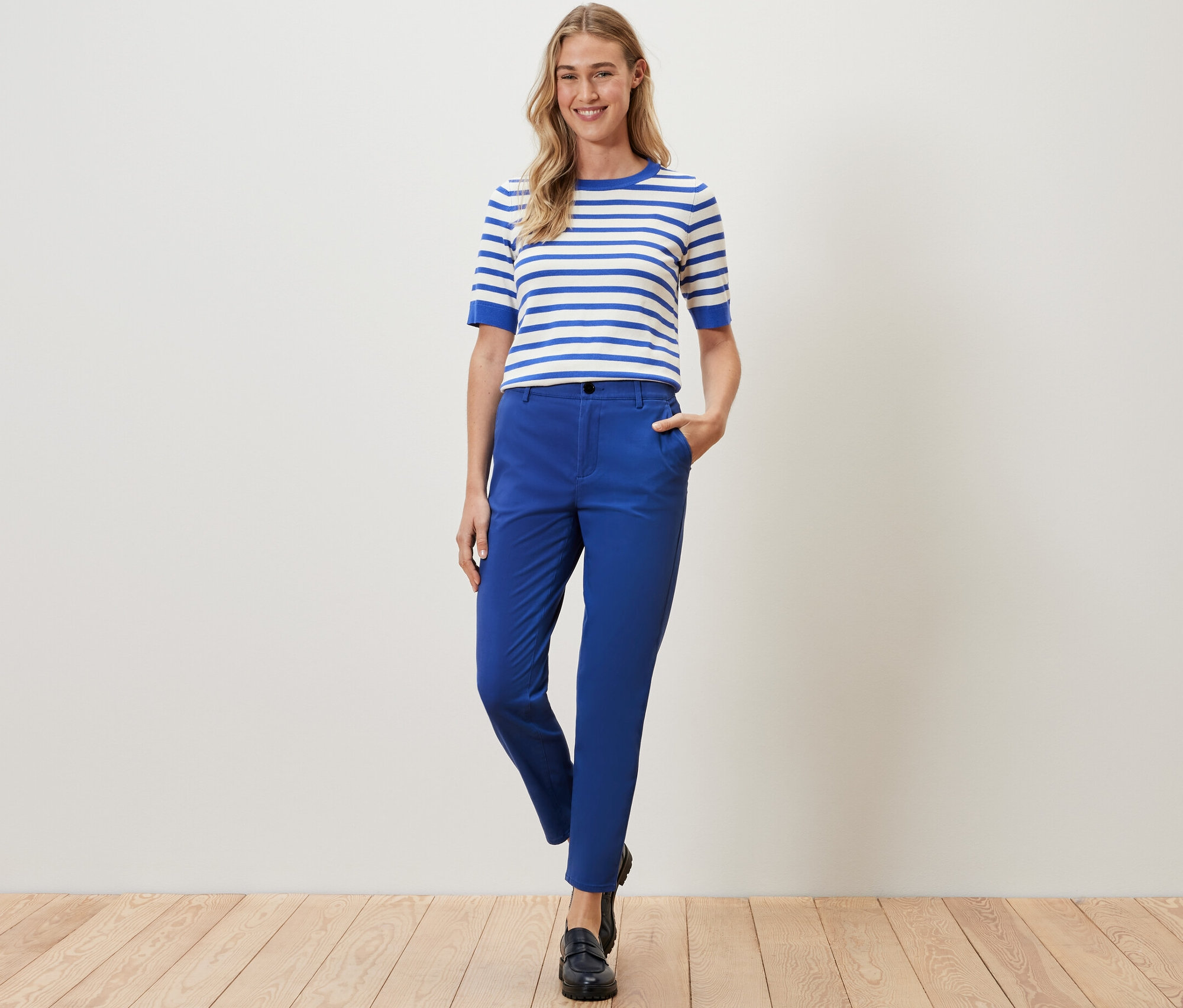 Frau posiert in kobaltblauen Chinos und einem gestreiften Oberteil.