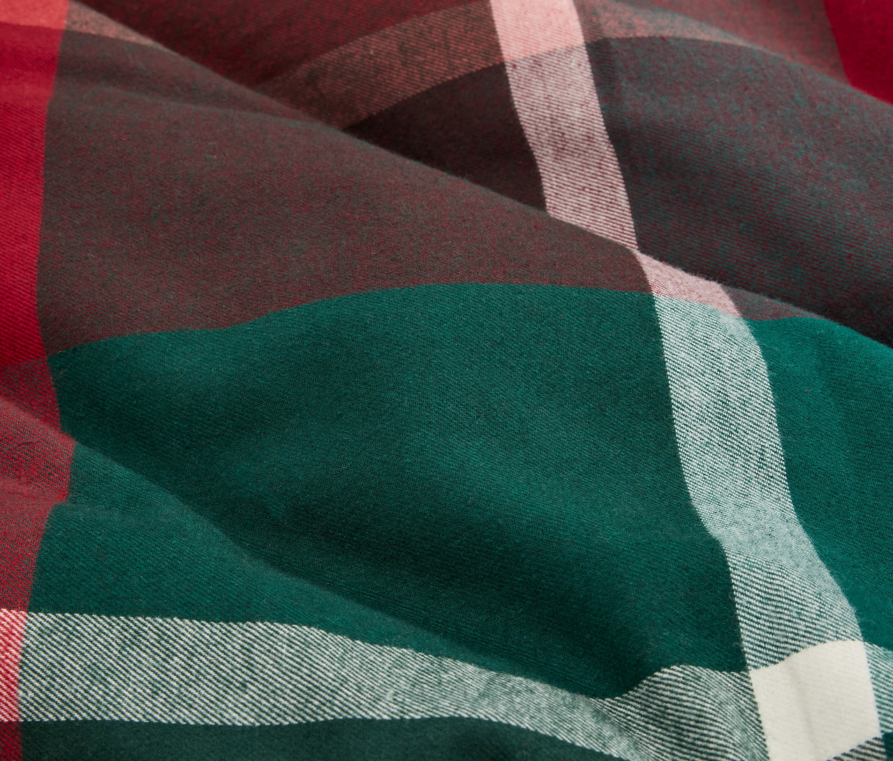 Detailaufnahme eines Stoffes mit Karomuster in Grün, Braun, Rot und Weiß.
