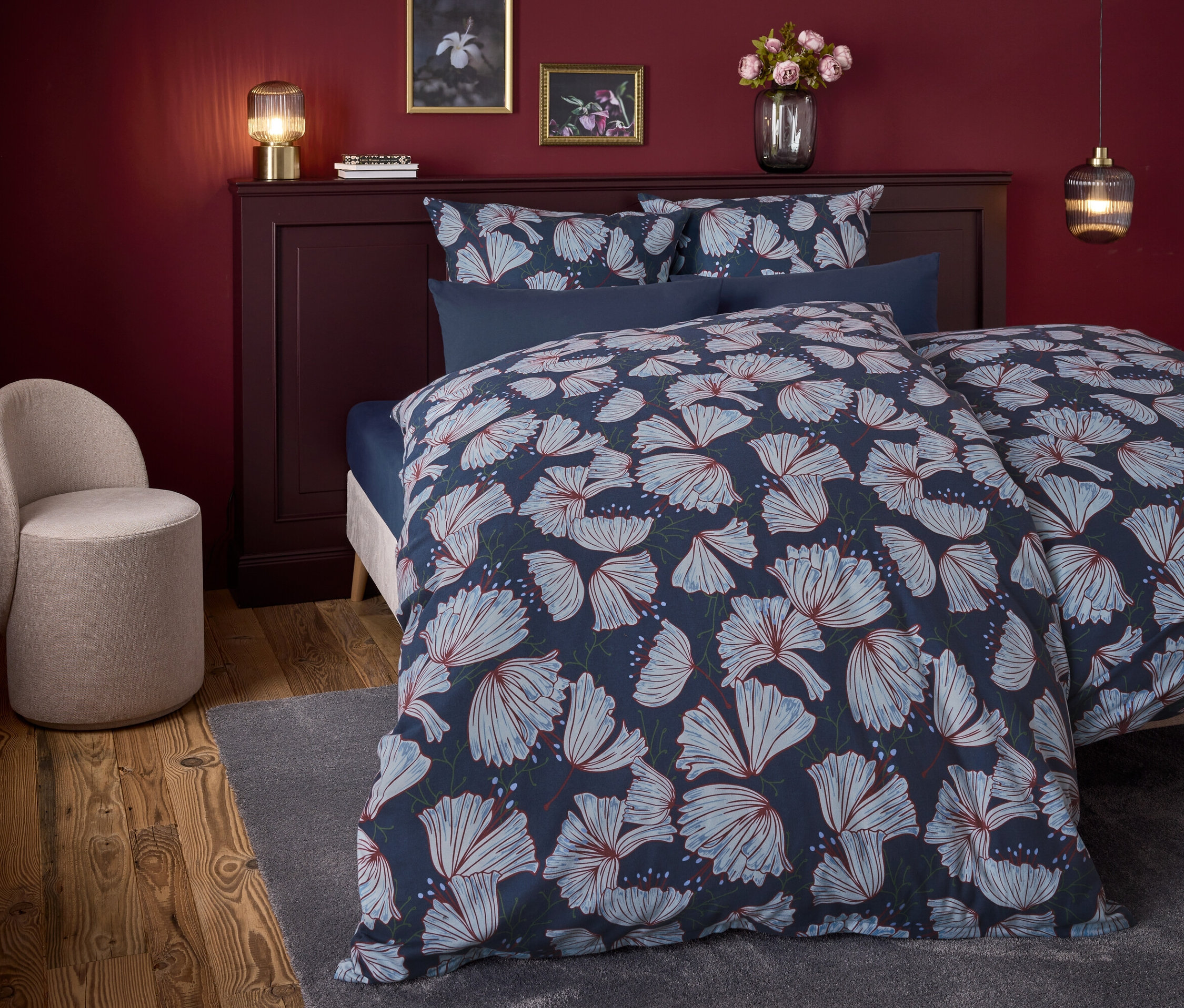 Schlafzimmer mit einem Bett mit blauem Blumendruck und einem beigen Sessel.