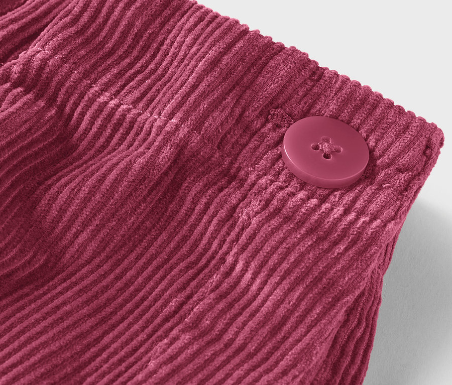 Detailaufnahme eines bordeauxroten Cordstoffs mit Knopf.