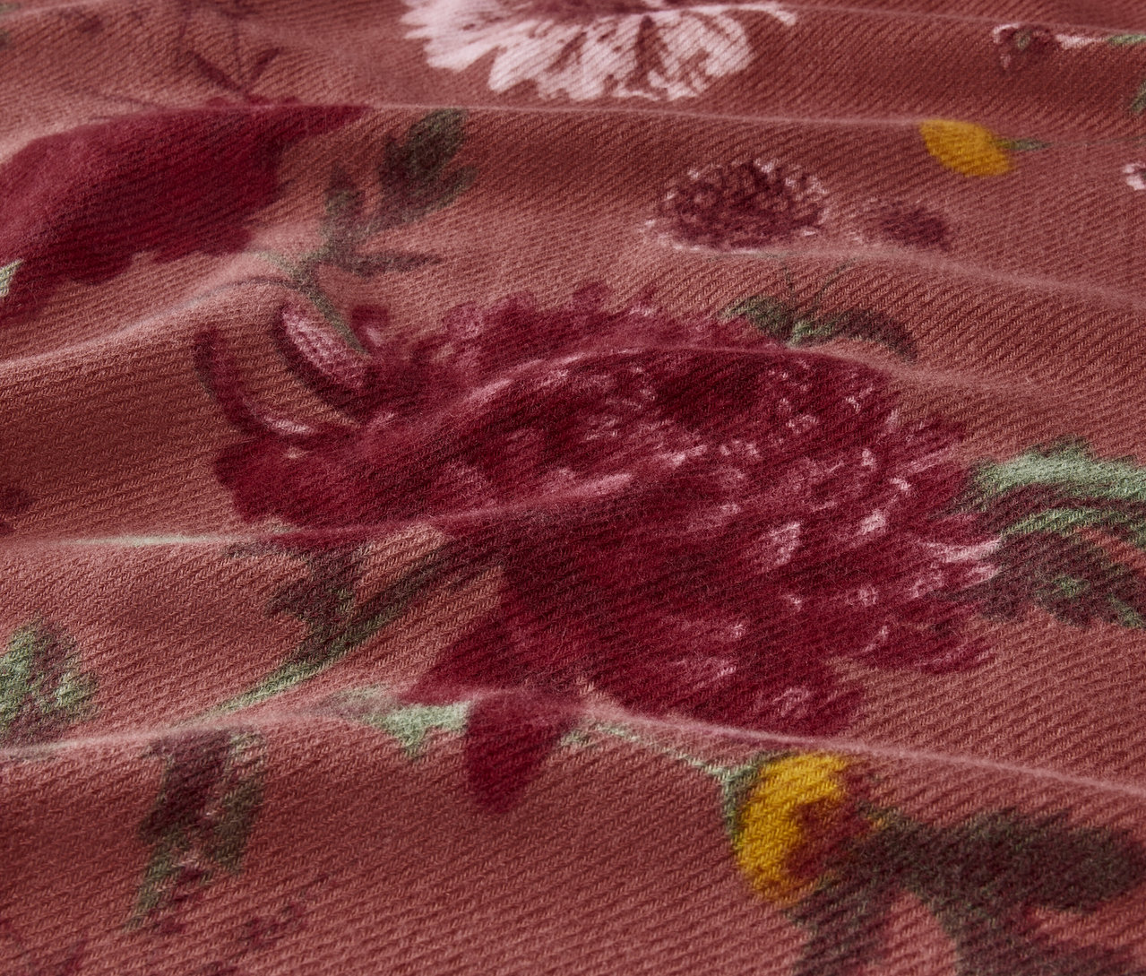 Nahaufnahme eines Stoffes mit Blumenmuster in Rosa- und Grüntönen.