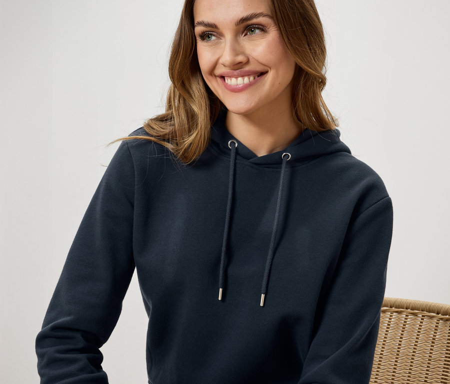 Eine lächelnde Frau trägt einen dunkelblauen Hoodie.