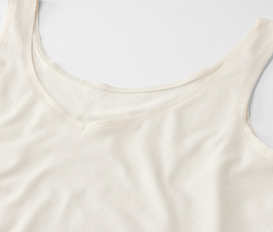 Detailansicht eines cremefarbenen Tanktops mit V-Ausschnitt.