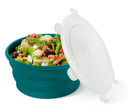 Salat in einer türkisfarbenen Schüssel mit losem, weißen Deckel.