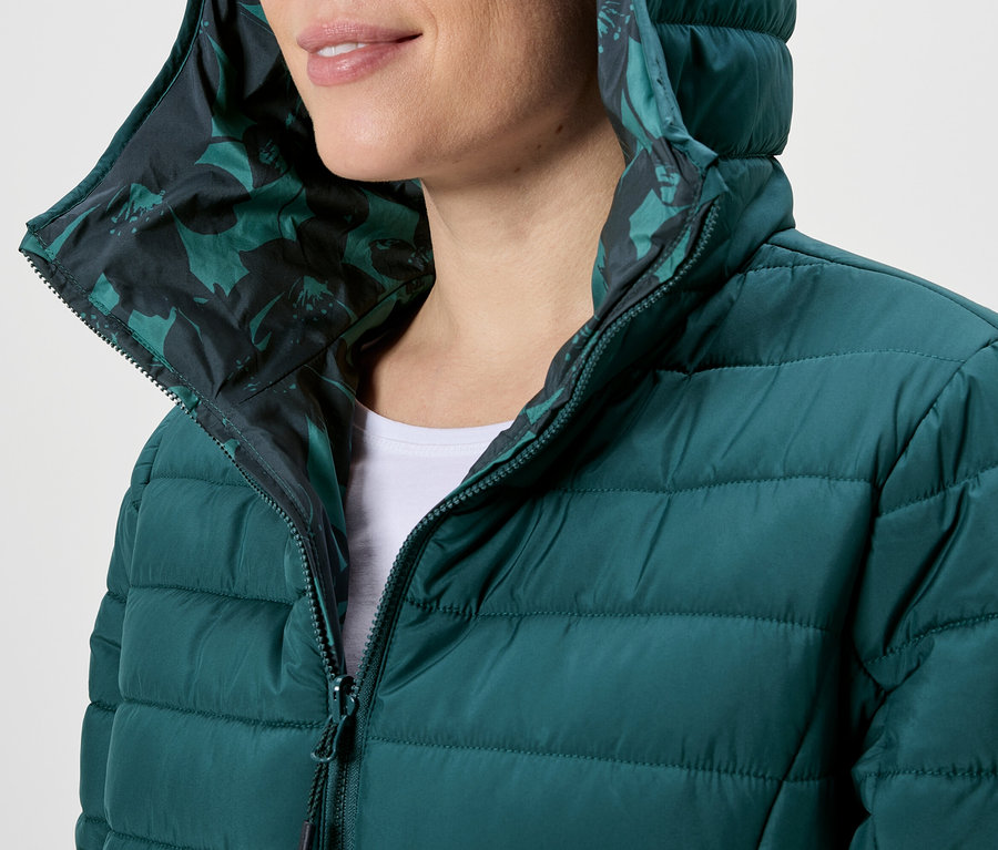 Frau mit Kapuze in grüner Steppjacke mit Reißverschluss und Blumenmuster.