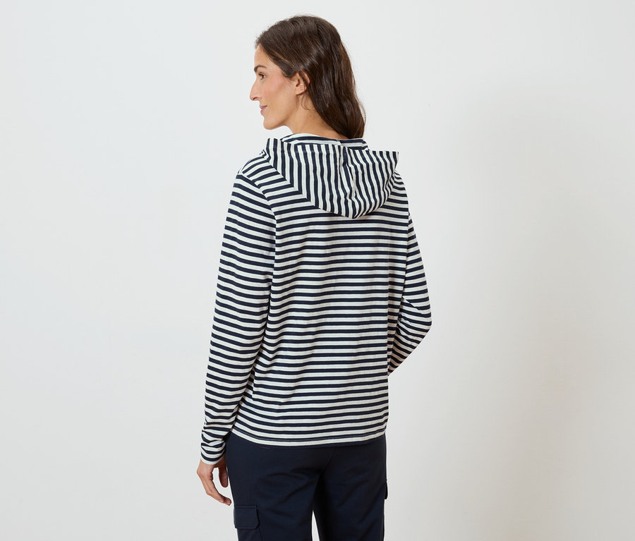 Frau von hinten, trägt einen gestreiften Hoodie und marineblaue Hosen.