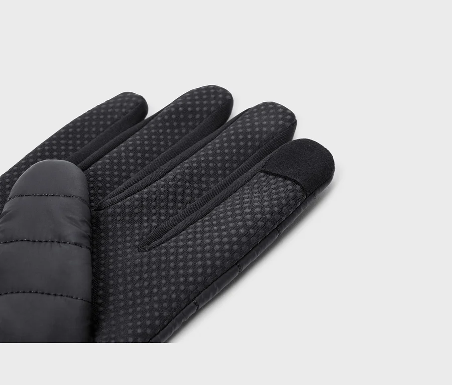 Nahaufnahme eines schwarzen Handschuhs, der die Handfläche und Finger zeigt. Die Handfläche und Finger haben ein gepunktetes Griffmuster, der Daumen ist gesteppt und die Zeigefingerspitze ist glatt für Touchscreens.